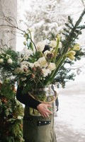 Person holding a vase of flowers with a snowy background